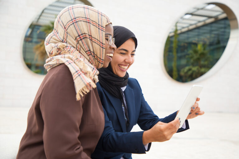 Happy female colleagues using tablet for video call